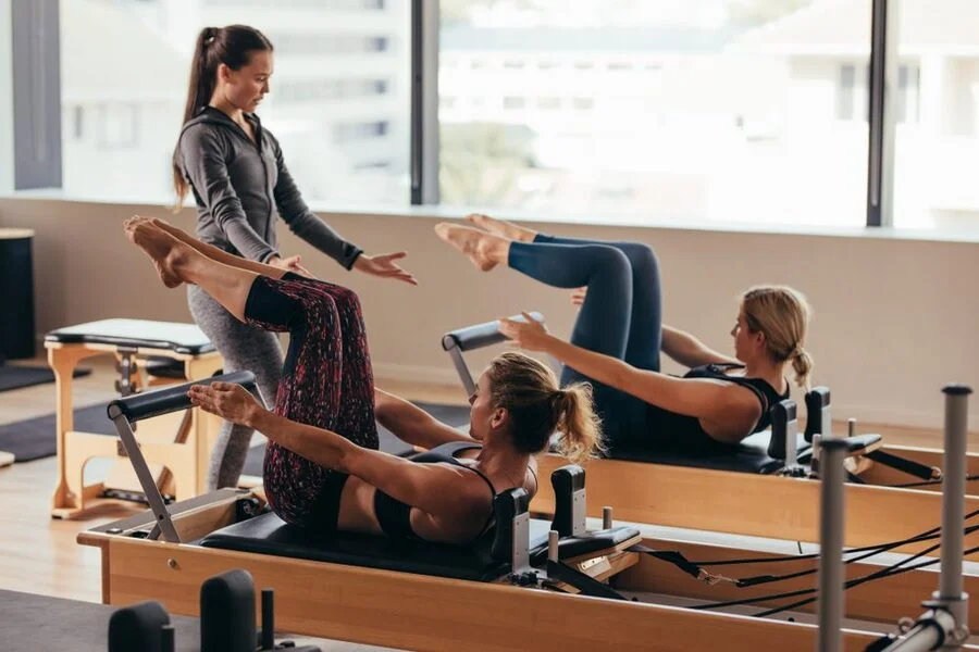 Practicando ejercicio físico y pilates chicas sobre máquinas