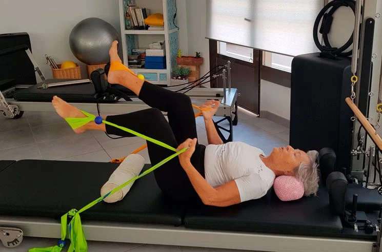 Mujer con cintas verdes practicando pilates en el post sobre problemas de artrosis