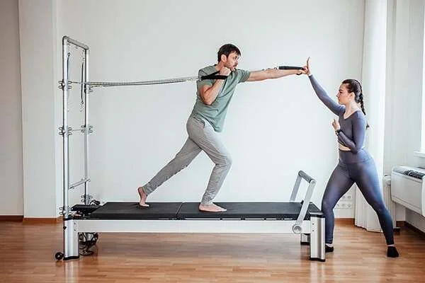 Chico y chica practicando pilates con máquinas en Alicante